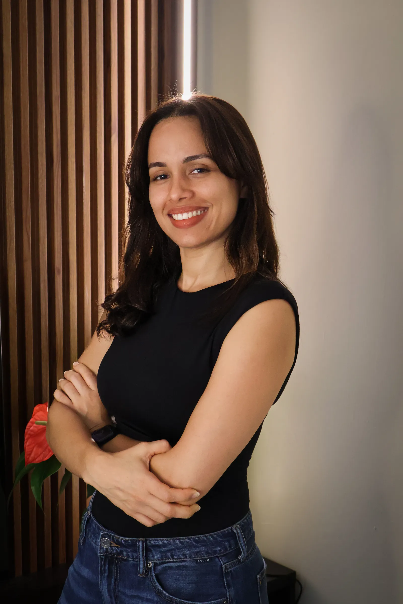 Daniela Sánchez sonriendo, con los brazos cruzados, frente a una pared de madera